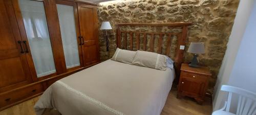 1 dormitorio con cama y pared de piedra en Subida san juan, en San Vicente de la Sonsierra