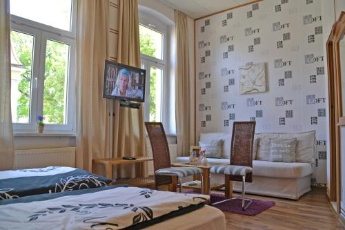 a bedroom with a bed and a couch and a tv at Pension zur Neiße in Guben