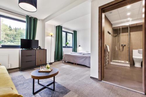 une chambre d'hôtel avec une salle de bains et une chambre dans l'établissement Hotel Zerrenpach Látky, à Látky