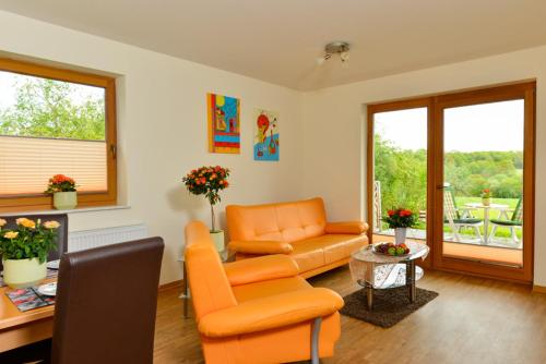 a living room with an orange couch and a chair at Hotel Zum Mühlental in Buch