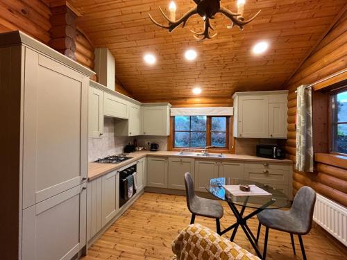 a kitchen with white cabinets and a table and chairs at Romantic Log Cabin With Hot Tub in Leominster
