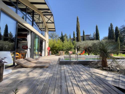 une terrasse en bois devant un bâtiment dans l'établissement VILLA Nîmes tourmagne PISCINE, à Nîmes