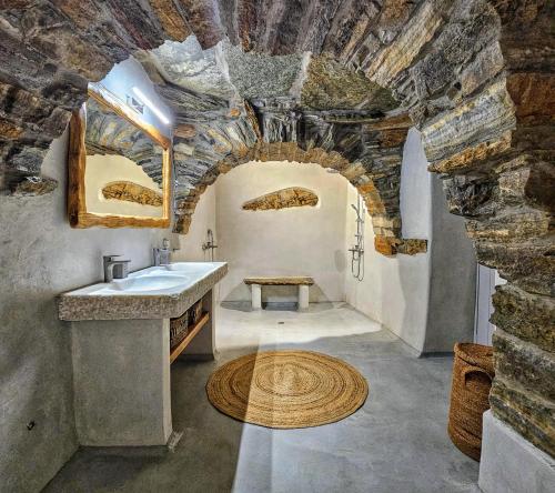 baño con lavabo y pared de piedra en Tinoshomelidays Residences en Venardatos