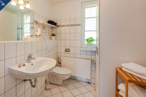 Baño blanco con lavabo y aseo en Waldsiedlung Waldhaus App 4.2 en Korswandt