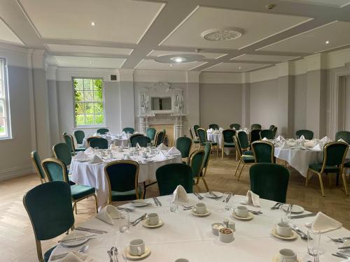 a banquet room with tables and chairs with white tablecloths at Park House Hotel in Shifnal