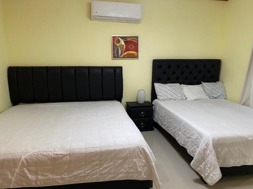 dos camas sentadas una al lado de la otra en un dormitorio en ApartaHotel El Bonao en Higuey