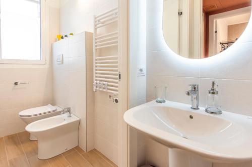 uma casa de banho com um lavatório, um WC e um espelho. em CaseOspitali - Glam Flat, nuovo trilocale di design zona Prada con box em Milão