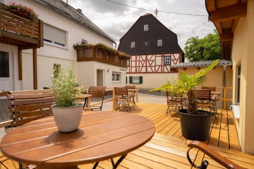 a wooden deck with tables and chairs and plants at Hotel Zum Mühlental in Buch