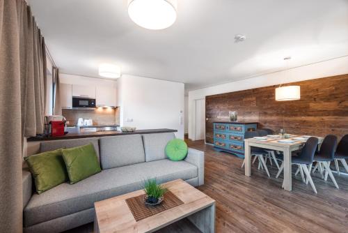 a living room with a couch and a table and a kitchen at AlpenParks Hotel & Apartment Orgler Kaprun in Kaprun