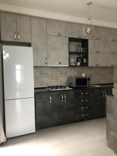 a kitchen with black cabinets and a white refrigerator at Квартира на море Батуми in Makhinjauri