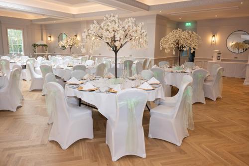 a banquet hall with white tables and white chairs at Park House Hotel in Shifnal