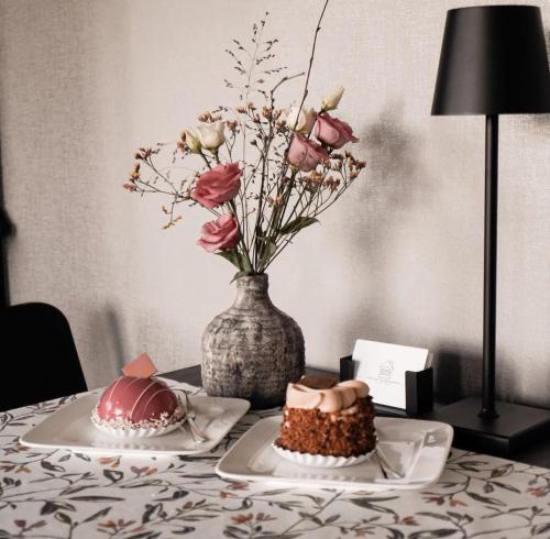 una mesa con dos pasteles y un jarrón con flores en B&B de Plattelandshoeve, en Rhenen