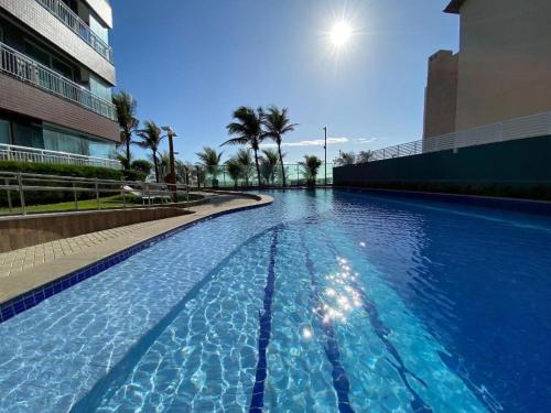 een groot zwembad met blauw water in een gebouw bij Beach Way - Apartamento no Porto das Dunas in Fortaleza