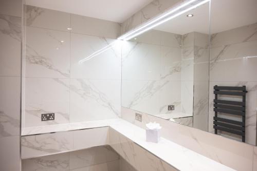 a bathroom with white marble walls and a mirror at Park House Hotel in Shifnal