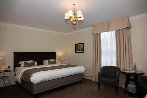 a bedroom with a bed and a chandelier and a chair at Park House Hotel in Shifnal