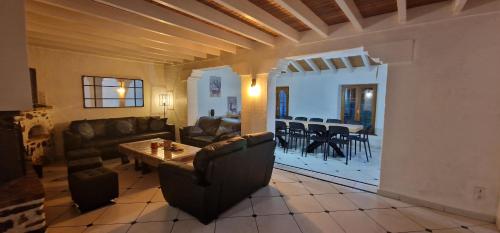 un salon avec des meubles en cuir et une salle à manger dans l'établissement Gîte de groupe La Gloriette, à Geu