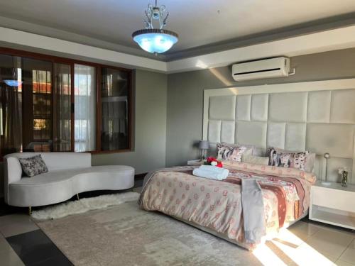 MatolaにあるCASA AZUL ACCOMMODATIONのベッドルーム(大型ベッド1台、ソファ付)