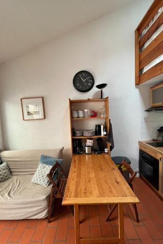 - un salon avec une table et une horloge murale dans l'établissement Maison de vacances plage des demoiselles St Jean, à Saint-Hilaire-de-Riez