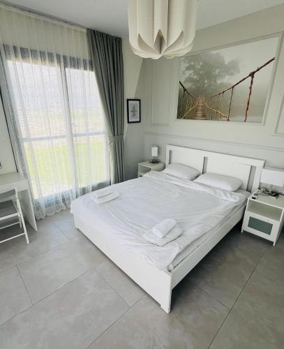 a white bedroom with a large white bed and a chandelier at Helena Resort & Spa in Kalecik