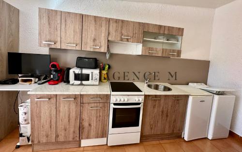 een keuken met houten kasten en een witte kookplaat bij STUDIO G in Calvi
