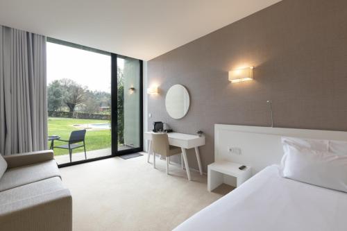 a hotel room with a bed and a desk and a window at Tempus Hotel & Spa in Ponte da Barca