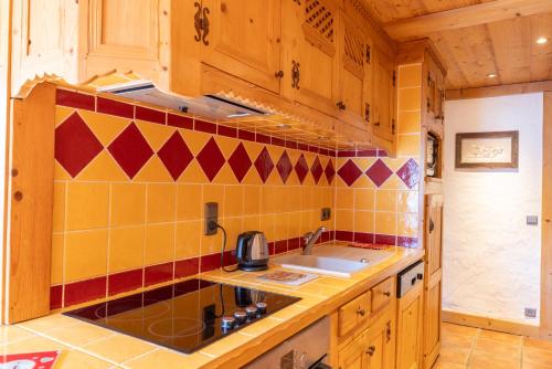 a kitchen with yellow and red tile on the wall at Appartement les 4 As in Megève