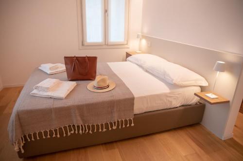 Una cama con un sombrero y un bolso encima. en Romantic White Apartment - 5 minutes from the lake, en Como