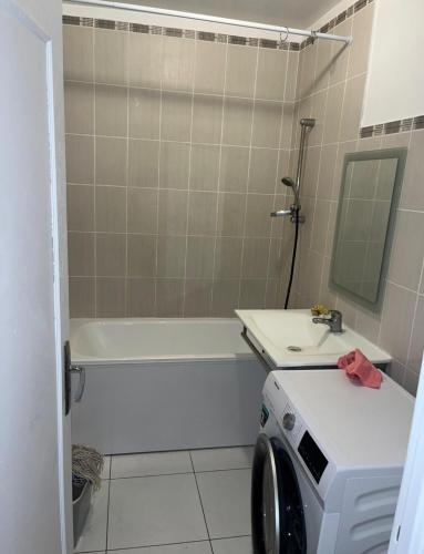 a bathroom with a tub and a sink and a washing machine at Belle chambre à louer in Sevran