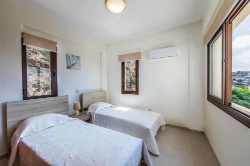 2 Betten in einem Zimmer mit 2 Fenstern in der Unterkunft Aqua Royal in Peyia