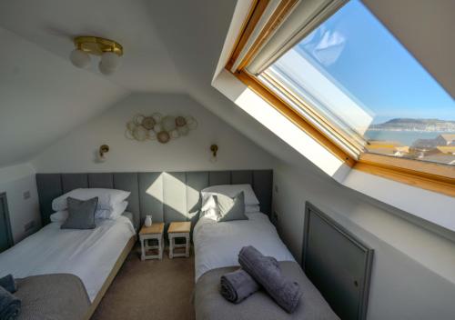 een slaapkamer op zolder met 2 bedden en een raam bij Pebble Cottage - Sea Views, Free Parking & Dog Friendly in Wyke Regis