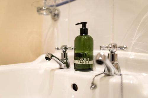 una botella verde de jabón está sentada en un fregadero en Aqua Marina - breathe in, relax en Pevensey