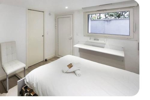 een witte slaapkamer met een wit bed en een raam bij Les Garennes in Rillieux