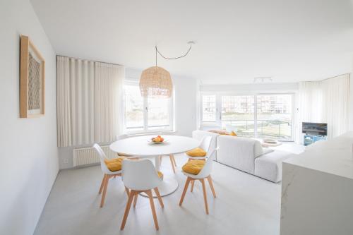 a white living room with a white table and chairs at Genieten in Groenendijk Oostduinkerke Koksijde - Vitamine Zee in Koksijde