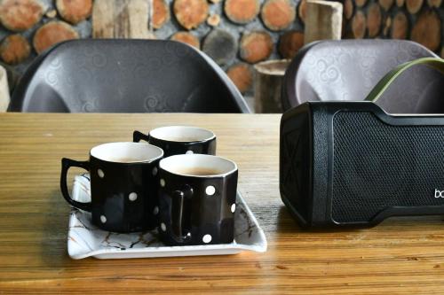 Hawk Camping & Cottages في ناينيتال: كوبين قهوة سوداوين على صحن على طاولة