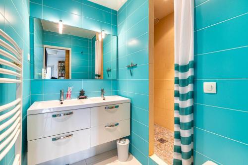 Baño azul con lavabo y espejo en GuestReady - Elevated Elegance near Panthéon, en París