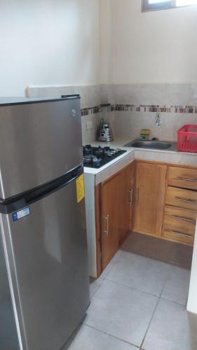 a kitchen with a stainless steel refrigerator and wooden cabinets at Hotel Palma Coco in Ayampe