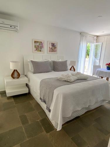a white bedroom with a large white bed and a window at Guest House Guarujá Hotel Boutique in Guarujá