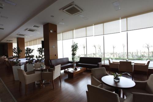 a restaurant with tables and chairs and large windows at Orucoglu Oreko Hotel in Manisa