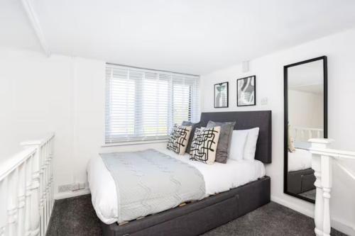 een witte slaapkamer met een bed en een spiegel bij Loft Style Apartment w/ Parking, in Leigh-on-Sea in Southend-on-Sea
