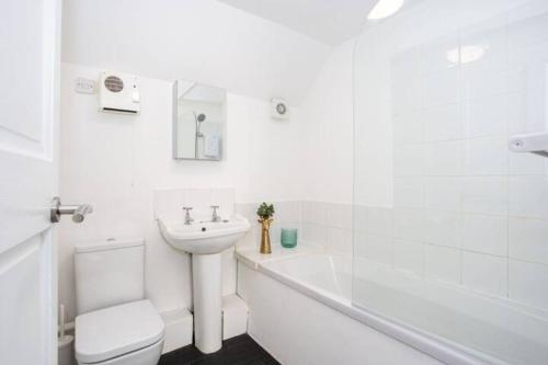 a white bathroom with a toilet and a sink at Loft Style Apartment w/ Parking, in Leigh-on-Sea in Southend-on-Sea