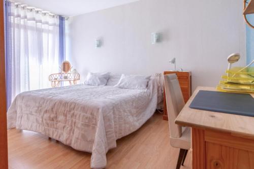 een slaapkamer met een bed met een tafel en een bureau bij Spacious air conditionned apartment with balcony in Béziers