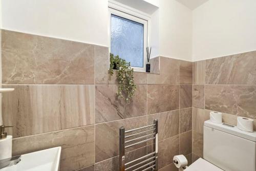 a bathroom with a sink and a toilet and a window at 4 BR House/Free Parking/5mins Walk To Kensal Rise in London