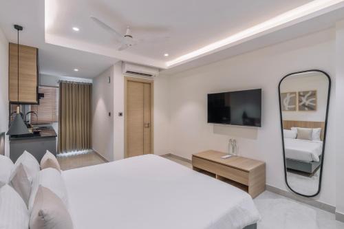 a white bedroom with a bed and a mirror at SKYLA Studios & Suites - Kondapur in Hyderabad