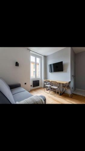 a living room with a couch and a tv at Appartement totalement rénové 4 couchage proche Lyon in Oullins