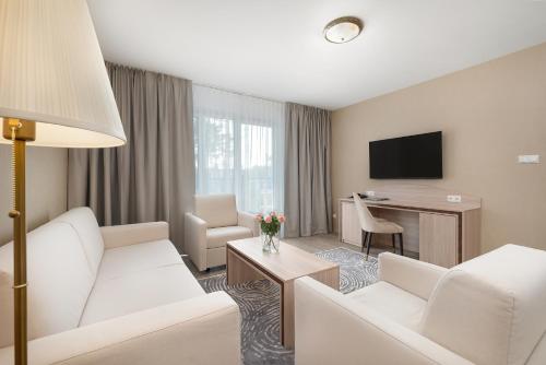 a living room with a white couch and a table at Juvena Hotel Wellness & SPA Adults Only 12 plus in Międzywodzie