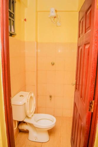 La salle de bains est pourvue de toilettes blanches et d'une porte rouge. dans l'établissement KIsumu Cozy One bedroom Apartment, à Kisumu