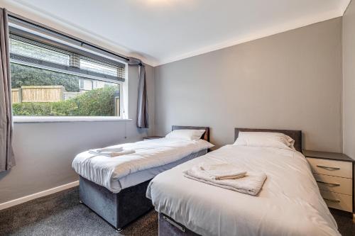 2 camas en una habitación con ventana en Lavish 2BR Bungalow Retreat in Birkenhead, en Birkenhead
