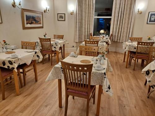 Somerset House B&B في غرانج أوفر ساندز: غرفة طعام مع طاولات وكراسي مع مفارش بيضاء
