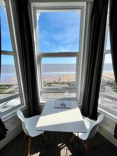 a table and two chairs in a room with two windows at Beaconsfield Holiday Apartments in Bridlington