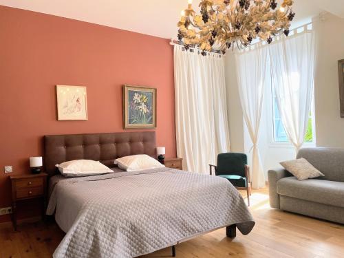 a bedroom with a bed and a chair and a chandelier at Maison d'hôtes Le Couvent in Bagnères-de-Bigorre